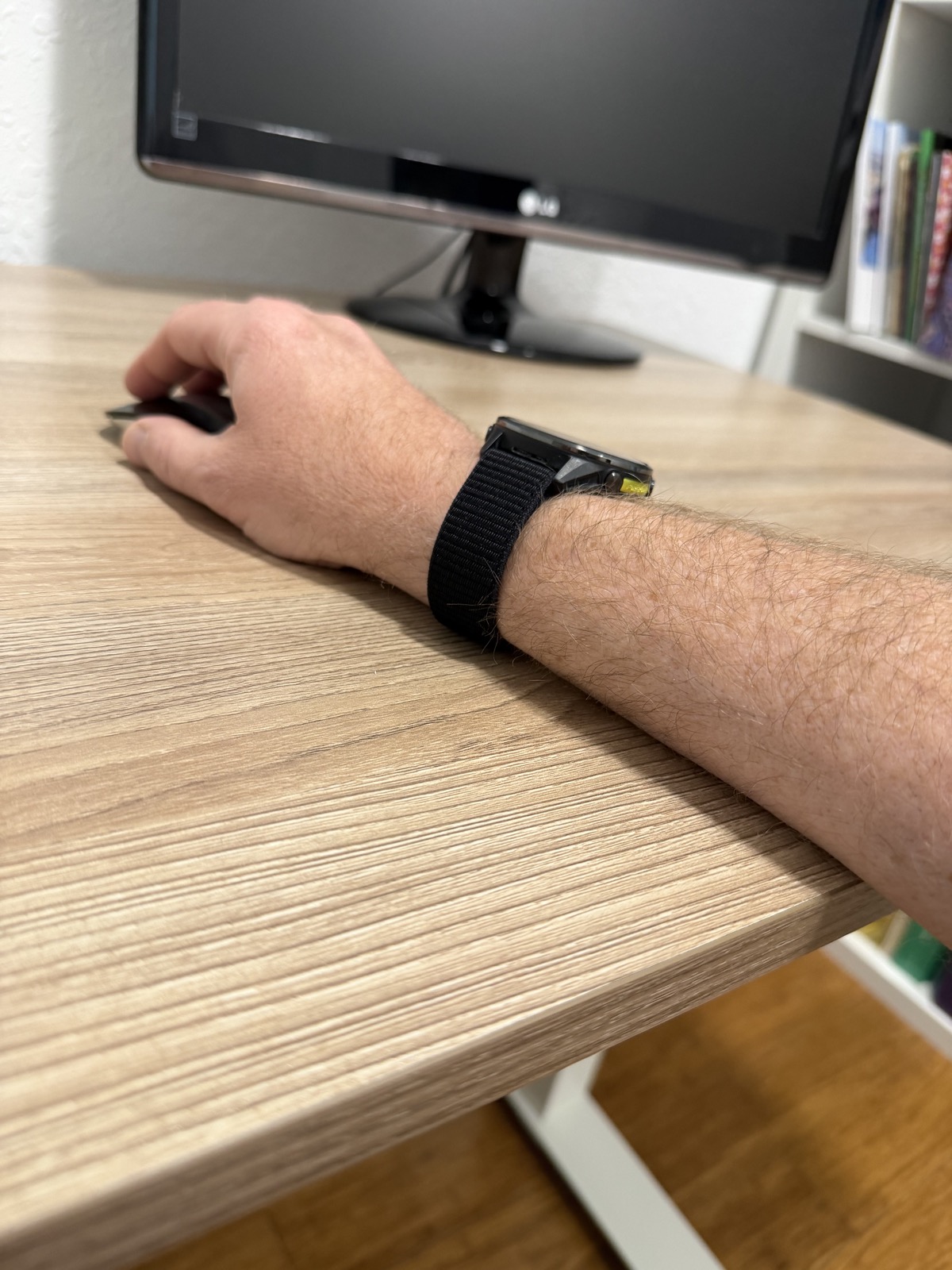 A forearm resting across the squared front edge of the SHW standing desk.