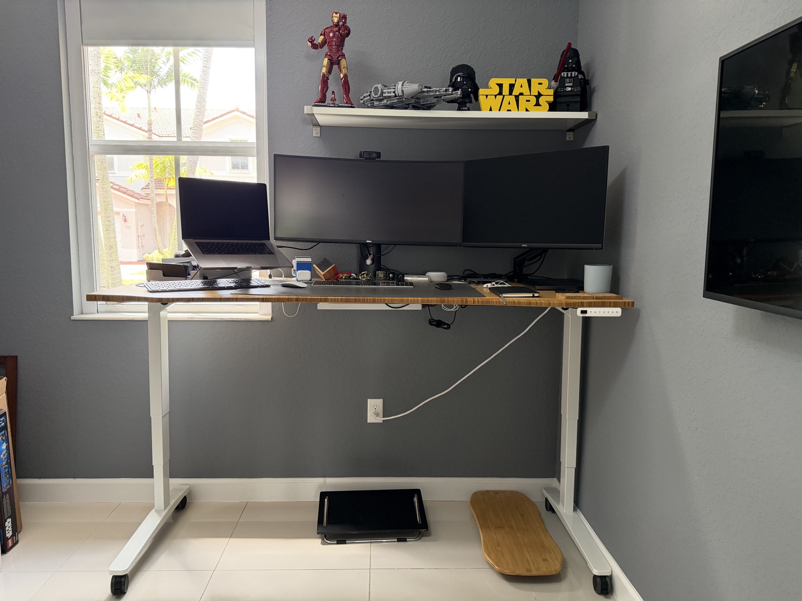The UPLIFT standing desk raised to standing height with multiple screens and visible cable slack.